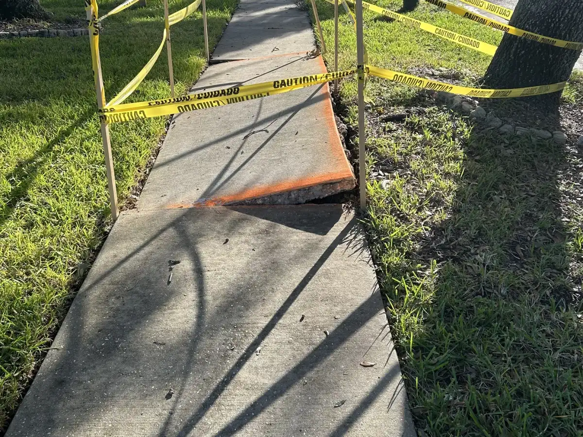 Lifted sidewalk panel marked for repair and the walkway after repair at a Tampa home